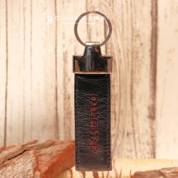 Detailaufnahme des 3 cm breiten Taschenanhängers aus Leder mit rotem Schriftzug destino.